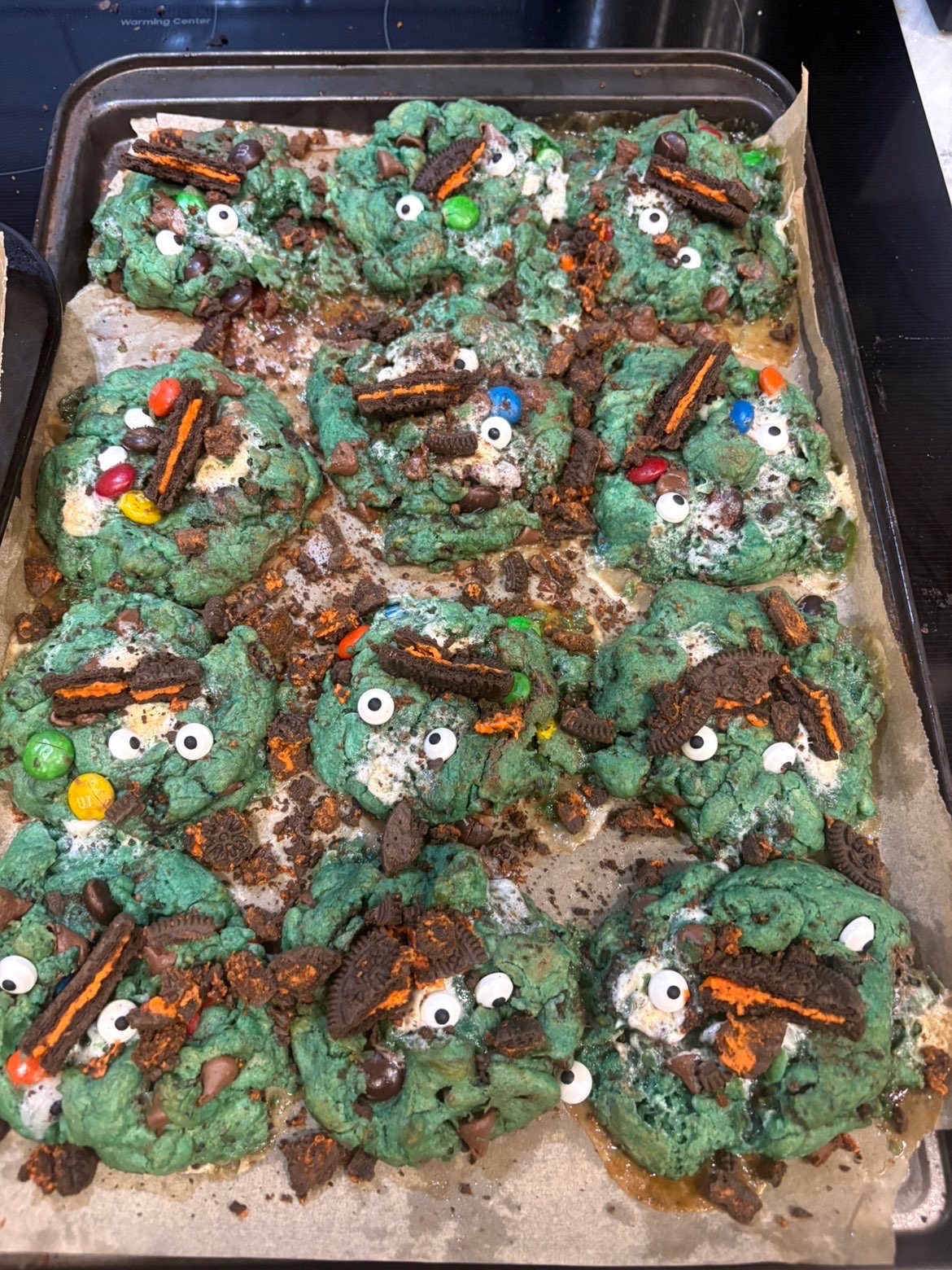 Tray of green monster cookies with candy eyes and Oreos