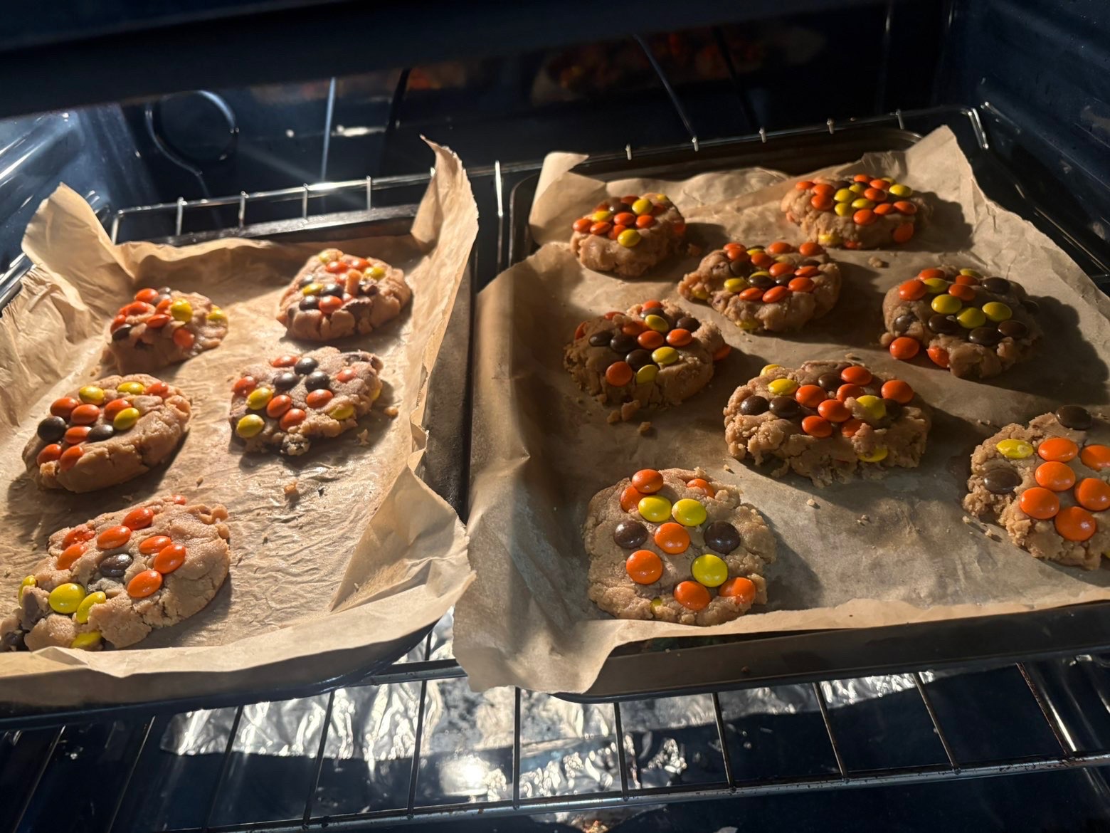 Trays of candy-topped cookies baking in the oven