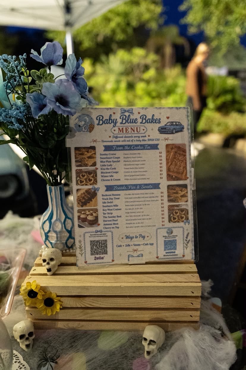 Baby Blue Bakes menu sign framed by blue flowers at the booth